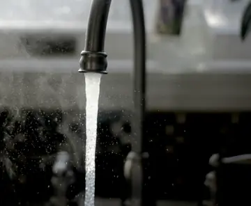 Torneira com água corrente em pia de cozinha